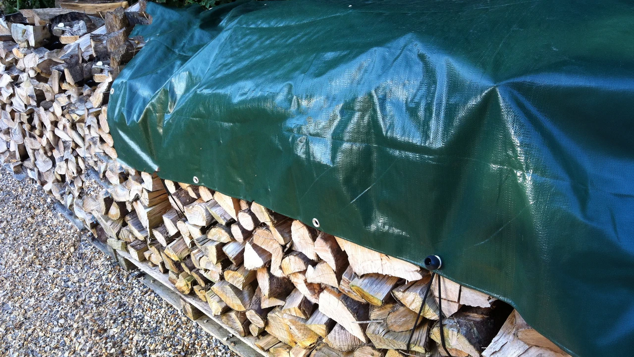 Green tarpaulin securely covering a stacked log store