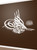 Bismillah (Tughra) islamic wall decal in white on a brown wall, along with English translation. Bismillah (Tughra) islamic wall decal in white on a brown wall, along with English translation.