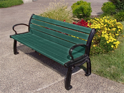 green recyled plastic park bench with colorful flowers behind it
