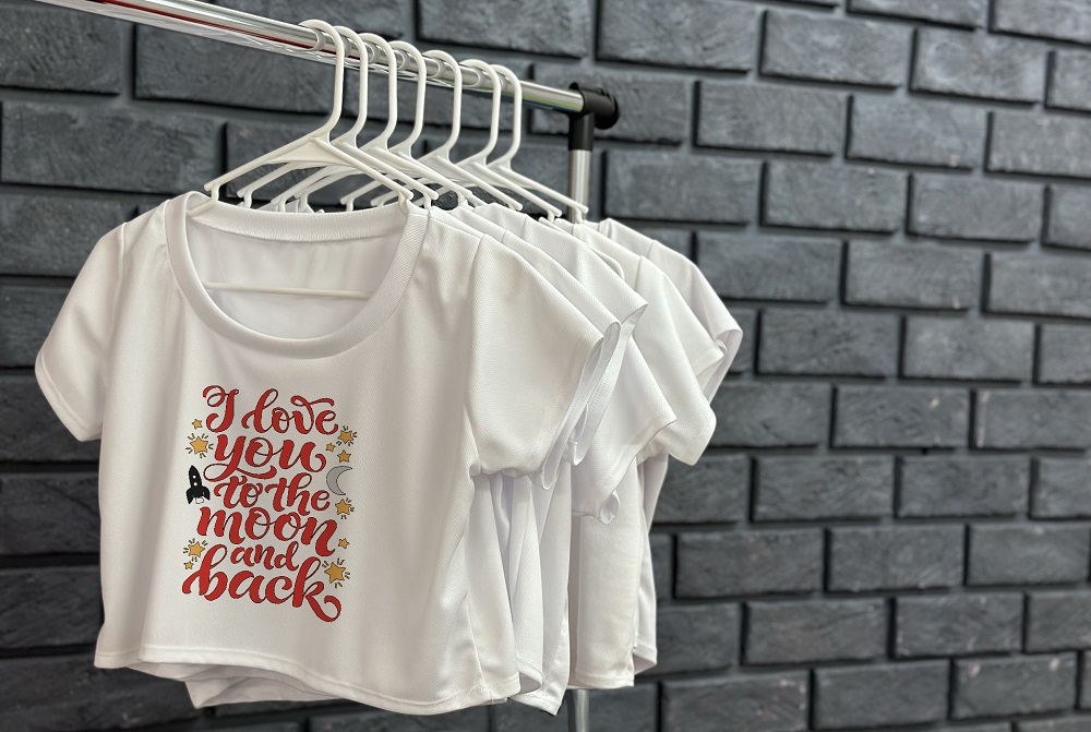 A White T-Shirt Hangs on a Rack Next to a Brick Wall