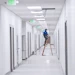 Installer on a ladder pulling cable above a corridor ceiling