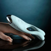 Couple's Therapy Multi-Zone Massager shown angled from the side in mint green. The curved flexible feelers extend upward and inward while the rounded base section and integrated finger loop are visible below. The profile view shows the slim flexible design and smooth silicone exterior.