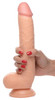 Woman's hand holding a large 10 inch realistic flesh-tone dildo with balls and suction cup base