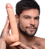 Master Cock Long Logan picture - Man holding a large realistic flesh-tone dildo with suction cup base