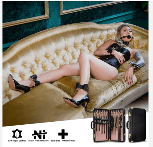 Model posed on a couch wearing wrist and thigh restraints from a bondage kit, showcasing luxury BDSM accessories in a styled setting