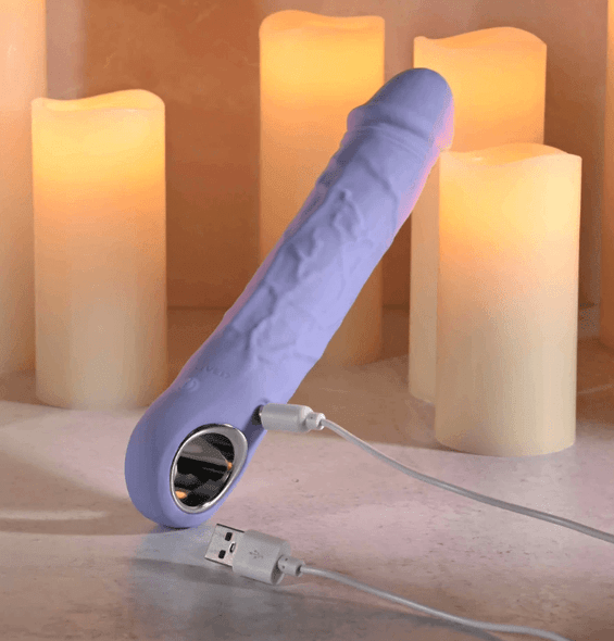 Purple Fantasy Realistic Vibe product image showing a purple realistic vibrator with raised vein detailing, rounded head, and chrome ring base resting at an angle on a flat surface.