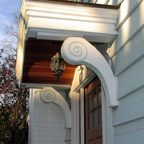 Large, white exterior architectural brackets, featuring a distinct S-shaped or curved scroll design