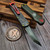Close-up of the Heretic Knives Manticore S Bounty Hunter featuring the camo carbon fiber back cover and red deep-carry pocket clip.