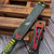 Detailed view of the Heretic Manticore S Bounty Hunter green distressed aluminum top scale with the deep-engraved red logo