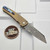 Pro-Tech Knives Malibu Flipper Blade Show Atlanta 2024 Distressed AlBronze "dragon scale" Handle, Irie Compound hand ground Damasteel Reverse Tanto 3.3" blade, mosaic pin push button, blue titanium clip PT-MBlade2024Damasteel