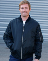 A man in a black soft shell jacket with a zip-up front and side pockets, standing against a grey background.