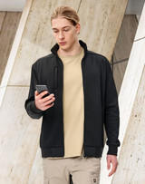 A man in a black fleece jacket holding a smartphone, set against a modern architectural background.