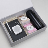 A gift box containing a black drink bottle, a notebook, a pen, a speaker, and assorted snacks.