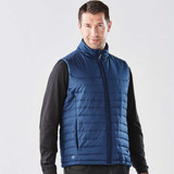 A navy quilted vest with a zip front, featuring a logo, worn over a black long-sleeve shirt.