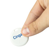 A white circular item tracker is held between fingers, featuring a logo on one side.