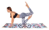 A yoga towel featuring a colourful geometric pattern, laid out under a person performing a yoga pose on a mat.