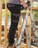 A pair of black work pants with grey accents, featuring pockets, being worn by a person on a ladder.