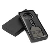 A gunmetal keychain in the shape of a house, elegantly packaged in a black box.