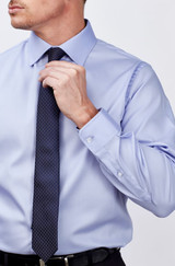 A light blue men's long sleeve button-up shirt with a polished look, paired with a navy tie. Features a logo.