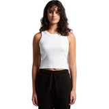 A woman wearing a white organic rib crop tank top, styled with black pants, standing against a plain background.