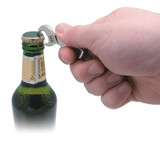 A drink bottle being opened with a silver DIY keyring bottle opener held by a hand. The bottle has a green glass body.