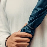A navy blue umbrella held by a person wearing a light-coloured top, featuring a logo.