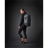 A woman in athletic wear stands sideways, carrying a grey Equinox 30 duffel bag with a logo.