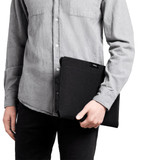 A laptop sleeve in black held by a person wearing a grey shirt, showcasing a sleek and minimalist design.