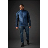 A men's hybrid jacket in navy blue, featuring a padded front and textured sleeves. The model is wearing jeans and black shoes.