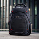 A black backpack with red accents, featuring multiple compartments and a logo on the front.