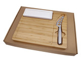 A bamboo cheese board set with a stainless steel knife and a white serving dish in a cardboard box.
