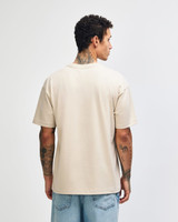 A light beige, unisex heavyweight t-shirt featuring a plain back design. It has a logo on the garment.