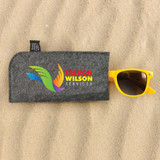 A gray sunglasses case featuring the logo of Faldon Wilson Services, with a pair of yellow sunglasses resting on top.