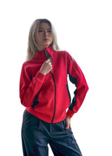 A woman wearing a bright red jacket with black accents, featuring a zippered front and a logo.