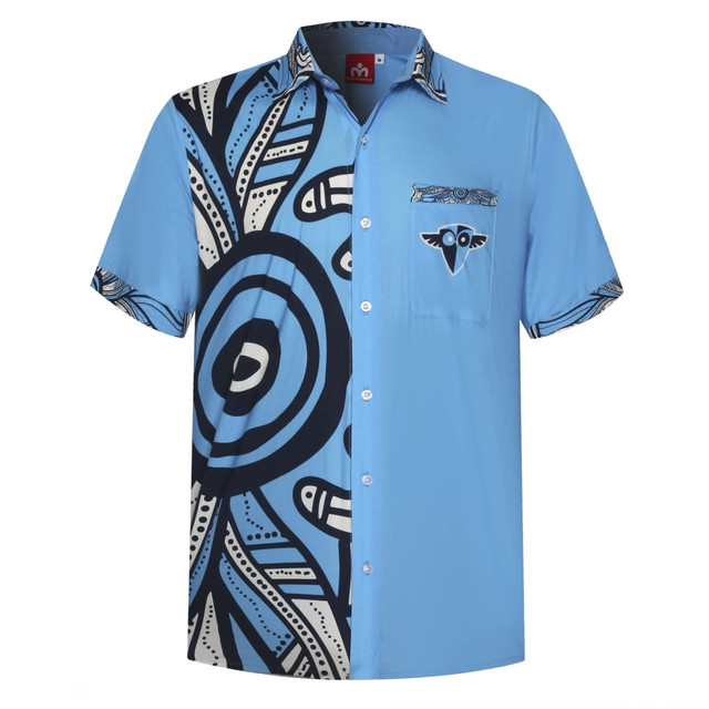 A short-sleeved shirt featuring contrasting blue shades with Aboriginal-inspired patterns and a logo on the pocket.