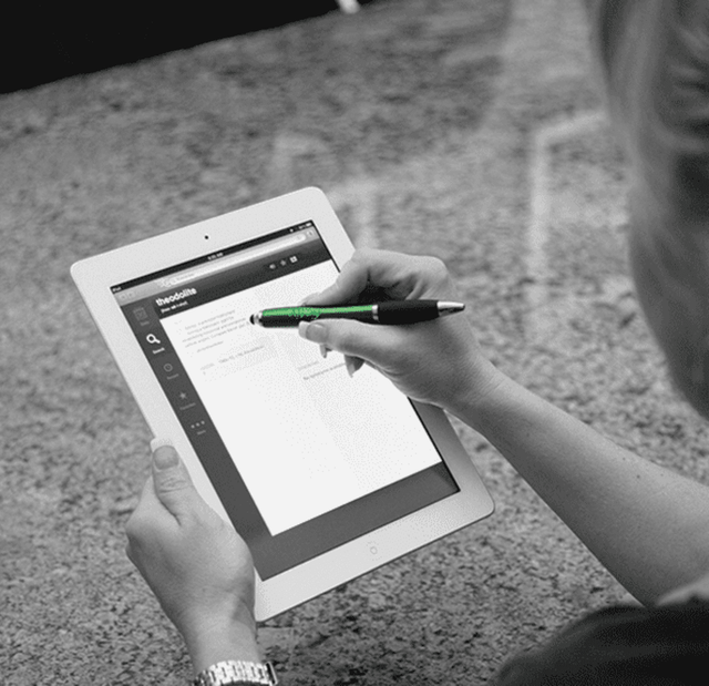 A person using a black stylus pen on a tablet, with a light-coloured background. The stylus has a sleek design and branding.