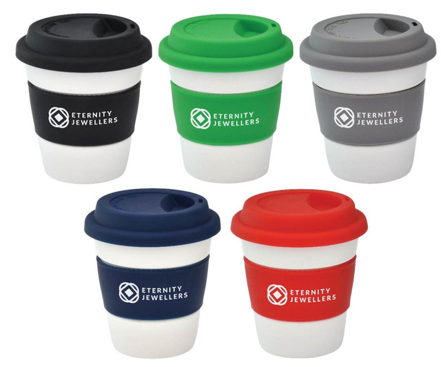A set of five reusable ceramic mugs in navy, green, red, grey, and black, each with a matching silicone lid and branding.