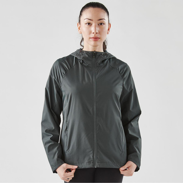 A woman wearing a dark grey women's Pacifica wind jacket with a hood, featuring a logo on the chest.