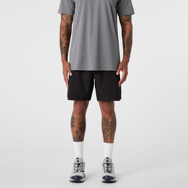 Black sports shorts are displayed, paired with a grey t-shirt and athletic shoes, featuring a logo.