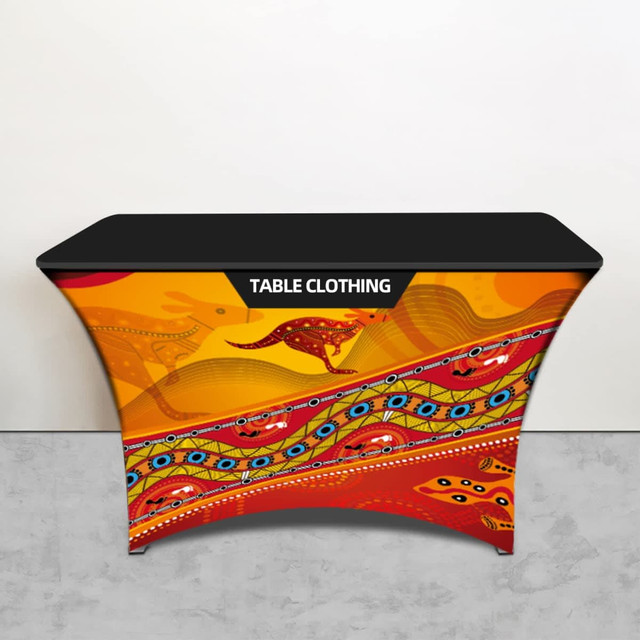 A table cloth featuring vibrant designs in orange, red, and blue, with abstract patterns and a logo at the top.