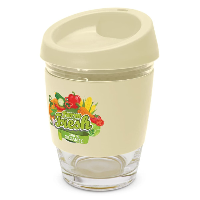 A reusable coffee cup in cream with a transparent base and a silicone lid, featuring colourful vegetable graphics and a logo.