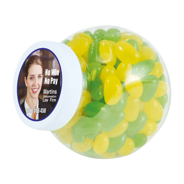 A clear container filled with green and yellow jelly beans, featuring a label with a logo and a portrait.