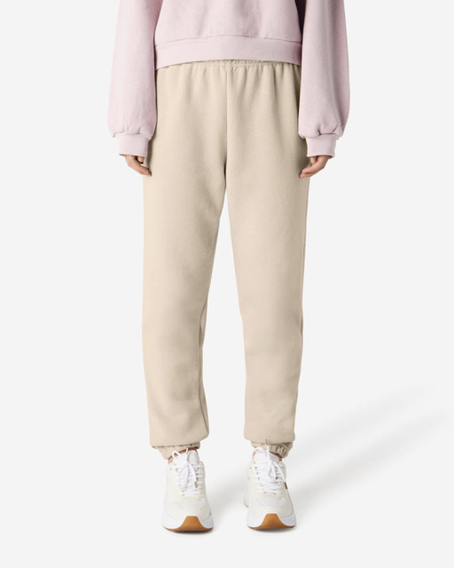 Unisex sweatpants in beige with an elastic waistband and cuffed ankles, paired with a light pink sweat top.