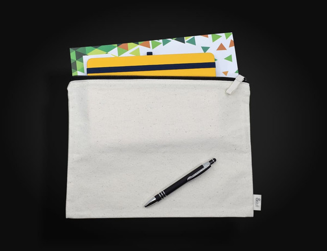 A cream-coloured conference bag featuring a zip closure, with a pen and assorted notepads visible inside.