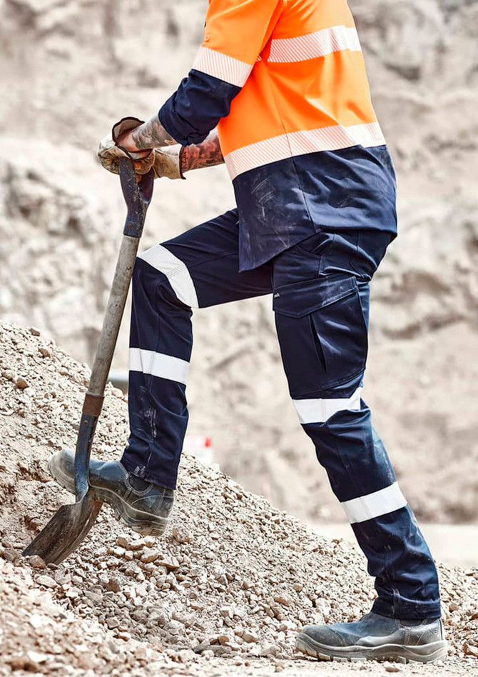 Mens Essential Stretch Taped Cargo Pant in navy blue with reflective stripes, worn by a person shovelling gravel.