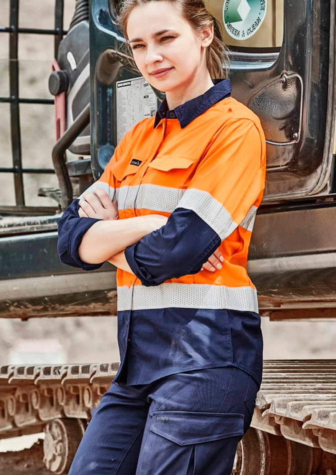 A long sleeve orange and navy work shirt with reflective tape, featuring a logo on the arm, displayed outdoors.
