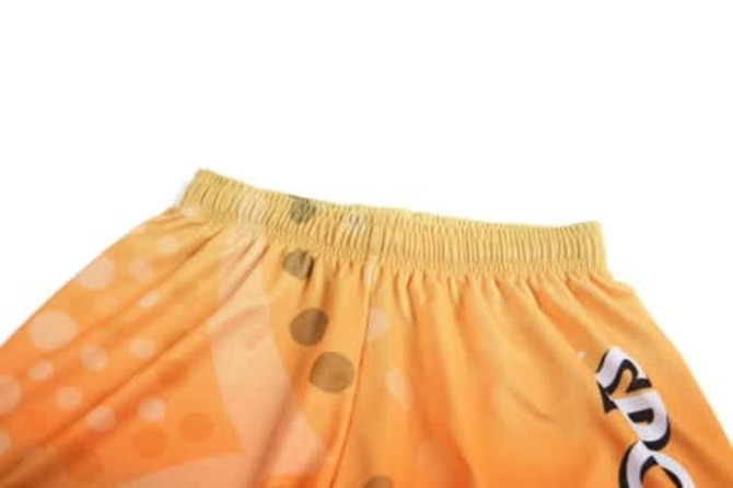An orange sports uniform featuring a stretchy waistband and a playful design with dots, accompanied by a logo.