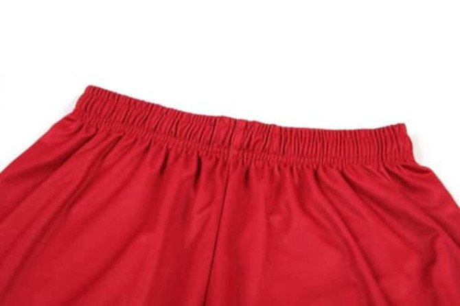 A red basketball uniform featuring an elastic waistband at the top. The fabric is smooth and lightweight.
