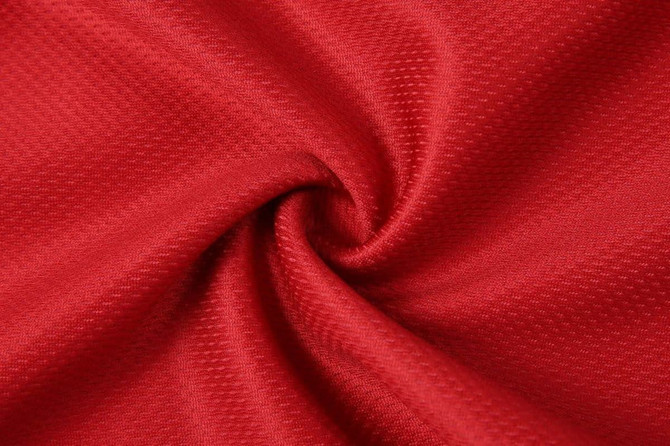 A close-up of red fabric with a textured surface, showcasing its weave and colour depth.
