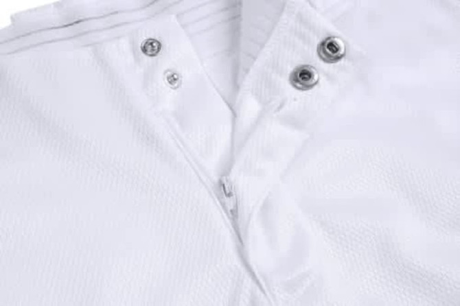 A white sports jersey featuring a zippered front and snap buttons, showcasing a textured fabric and an attached logo.